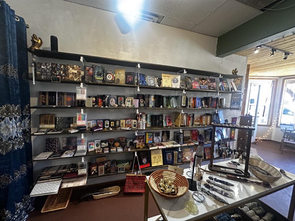 Wall shelves filled with books, tarot decks, and oracle decks